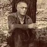 Photo de William Carlos Williams assis au pied d'un arbre.